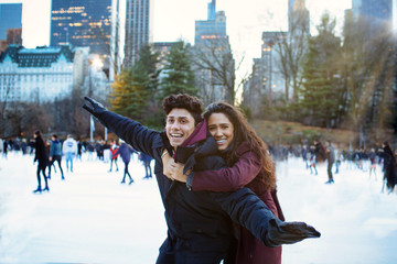 Portrait of a happy young couple smiling, hugging and having fun while ice skating outside in Central Park, NYC
