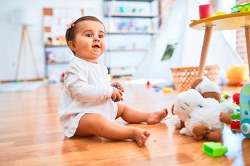 Beautiful infant happy at kindergarten around colorful toys