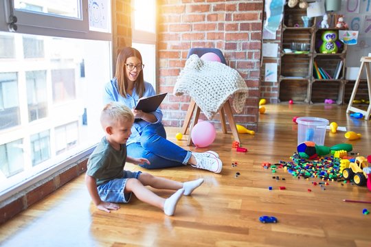 Young therapist woman speaking with child, counselor and behaviour correction at the office around toys