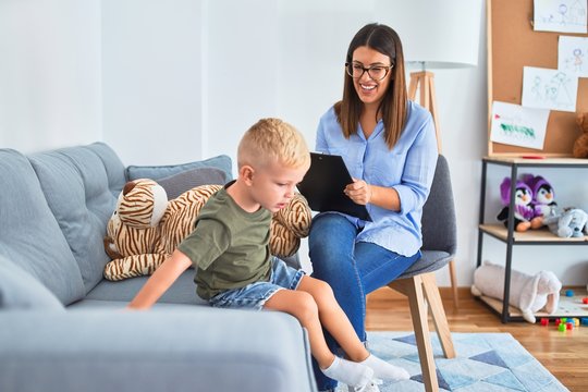 Young therapist woman speaking with child, counselor and behaviour correction at the office around toys