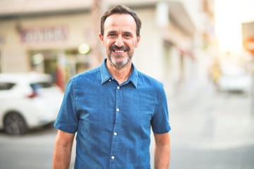 Middle age handsome man standing on the street smiling