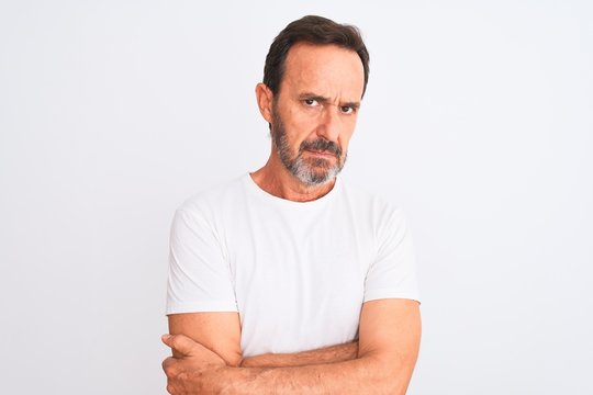 Middle age handsome man wearing casual t-shirt standing over isolated white background skeptic and nervous, disapproving expression on face with crossed arms. Negative person.