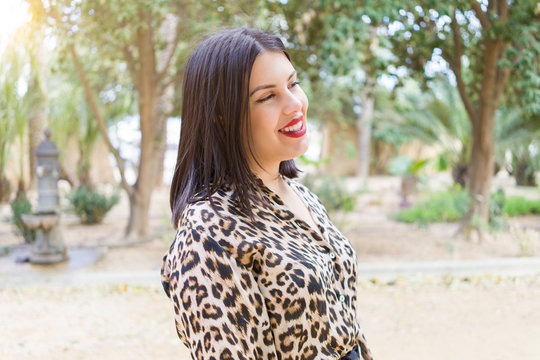Young beautiful woman with red lips smiling happy at garden