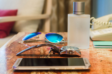Accesorios para hombres para gente de negocios. Reloj de mano, teléfono celular, gafas de sol,botella de perfume sobre fondo de madera. Elegancia y lujosos accesorios para caballeros. Cuidado personal