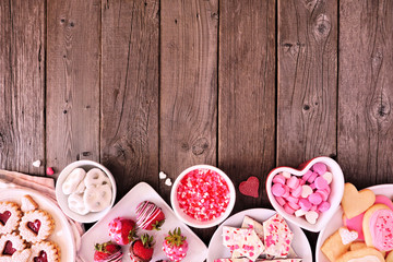 Valentines Day bottom border of assorted sweets and cookies. Above view over a wooden background. Love and hearts theme. Copy space.