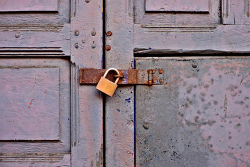 Old grungy door locked with a latch and a padlock.