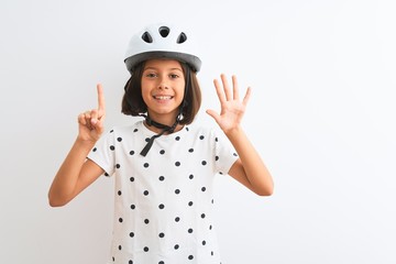 Beautiful child girl wearing security bike helmet standing over isolated white background showing and pointing up with fingers number six while smiling confident and happy.