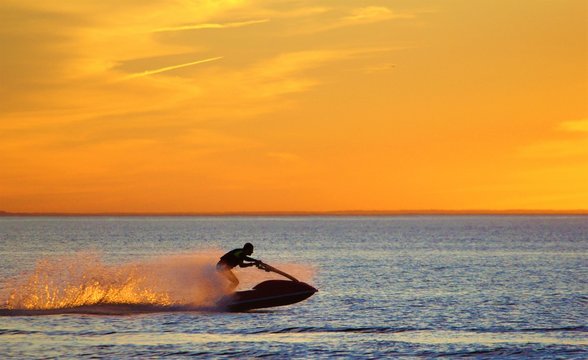 silhouette of man on a jet ski boat at sunset