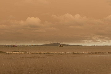 A haze from Australia's bushfires hangs over Torbay Beach, North Shore district of Auckland, New Zealand.