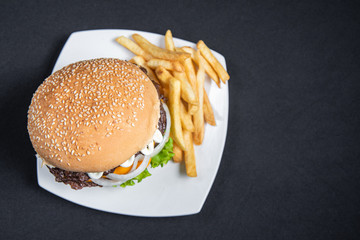 Hamburger and french fries on the plate on a black background