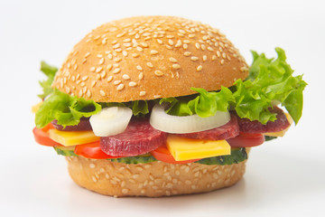 Hamburger with vegetables and sausage on a white background. Fast food and breakfast. Calories and diet.