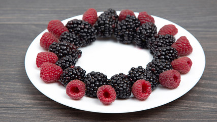 raspberries and blackberries on a white plate. Vitamin and Diet Food