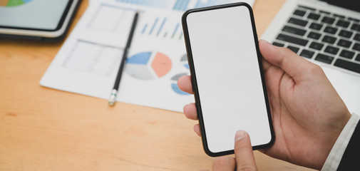 Cropped shot of young businessman working on his project while using blank screen smartphone