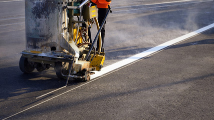 Low section of road worker with thermoplastic spray road marking machine working to paint traffic...