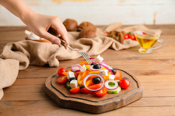 Woman eating fresh Greek salad at table