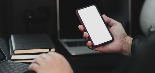 Close-up view of businessman using smartphone while working on his project in dark luxury workplace