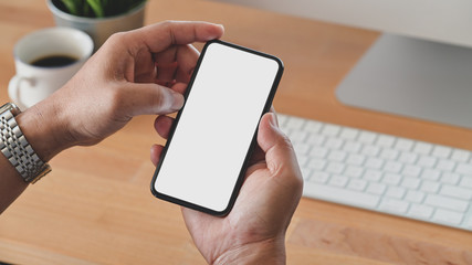 Cropped shot of young man holding blank screen smartphone