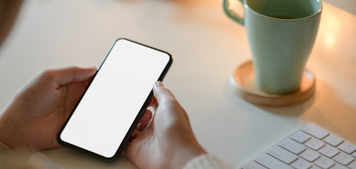 Cropped shot of businesswoman holding blank screen smartphone with bokeh light background