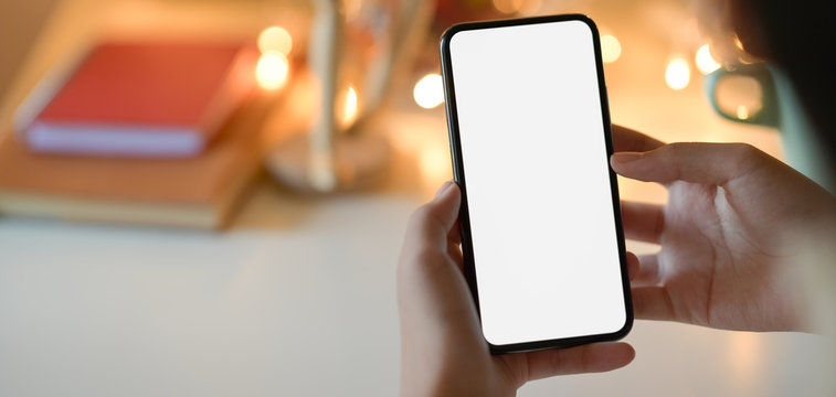 Close-up view of businesswoman holding blank screen smartphone with bokeh light background