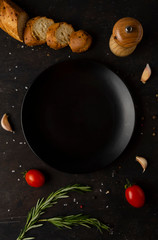 empty dark plate and fresh seasoning, spoon and vegetables ingredients