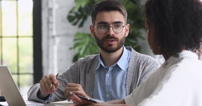 Professional caucasian mentor helping african intern with corporate software