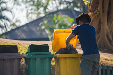 Man throws the black plastic bag with rubbish in to the general waste bin in the national park.