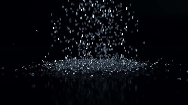 Diamonds falling down onto a mirrored black surface against black. CGI (Computer Generated Image). Slow pan down