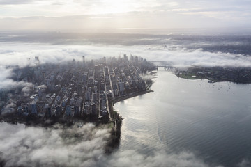 Downtown Vancouver, British Columbia, Canada. Aerial View of a modern city on the West Coast of Pacific Ocean during a cloudy sunrise and covered in Fog.