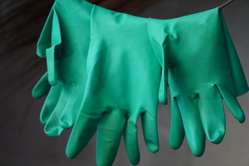 Green rubber gloves hang on unhygienic steel wires.