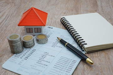 Orange roof houses, a pile of coins with accounts of income and expenses, ideas for saving money to buy a house for the future, home mortgage and real estate, business investment tax. Business growth.