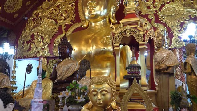 A slow motion reveal of the main Buddha and statues at a Buddhist Temple in Chiang Rai, Thailand. 4K medium.