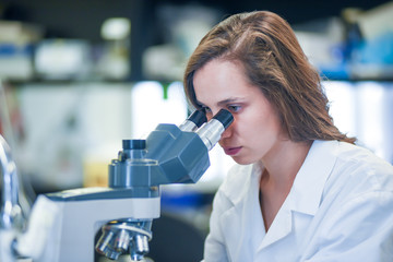Female scientist working with microscope in biomedical laboratory 