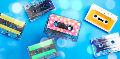 Retro cassette tape collection on blue background with bokeh, top view.