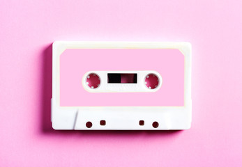 Pink retro cassette tape on pink background, top view.