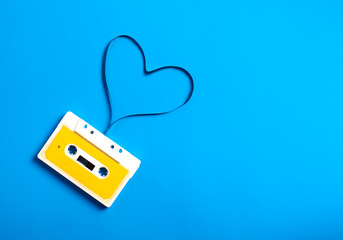 Retro cassette tape with tape in the shape of heart on blue background. love concept, top view,...