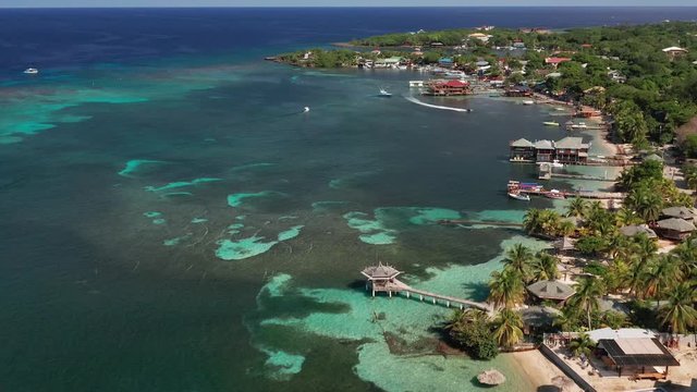 Wide aerial over reef, shoreline, docks, of West End, island of Roatan