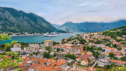Fototapeta na wymiar The picturesque town of Kotor, Montenegro, and its long bay and surrounding mountains, as a cruise ship enters the sheltered harbor.