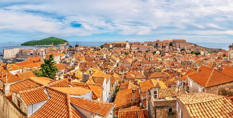 A high angle, panorama view of the entire walled Old Town of Dubrovnik, with Lokrum Island and the Adriatic Sea in the background.