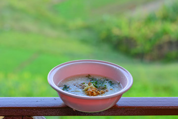 A cup of pink boiled rice with a backdrop of mountain views and a mild morning sun in the winter.