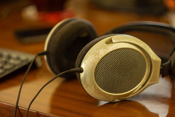 Old headphones on a table with a keyboard, closeup with blurry background
