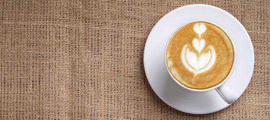 Cup of coffee latte art with plate and space on jute panoramic