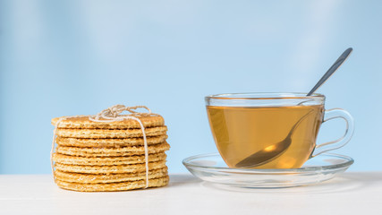 Homemade waffles with tea on a white table on a blue background.