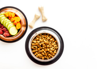Ingredients of dry feed for dogs - meat, vegetables - near bones on white background top-down copy space
