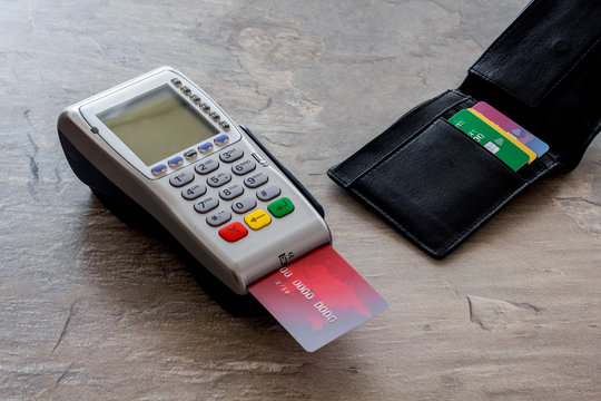 Bank terminal for payments and plastic card on grey stone background