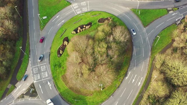 Aerial view of cars and a truck on a roundabout in the UK. Roundabout centre with grass and trees in the beautiful UK countryside.