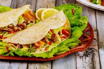 Soft tortillas stuffed with lettuce, meat and cheese on wooden background. Mexican food concept.