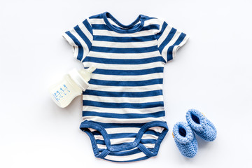 Blue bodysuit for baby boy near children's accessories on white background top-down
