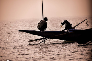 silhouette of a man on a boat in a lake 