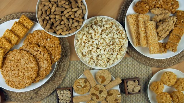 Zoom out shot of beautifully plated items for Punjabi's Lohri festival in India. Top vies shot of popcorns  roasted groundnuts  murmura ladoos  rewri  dry fruit gajaks  gajak rolls  and peanuts chi...