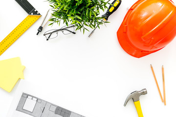 Builder work desk with hard hat, instruments and blueprints on white background top-down frame copy...